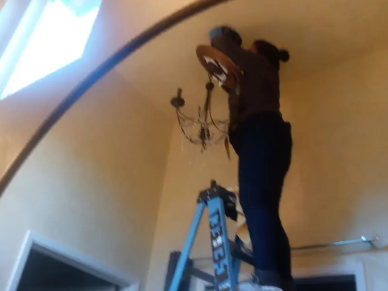 Electrician installing a chandelier in a Ridgefield residence